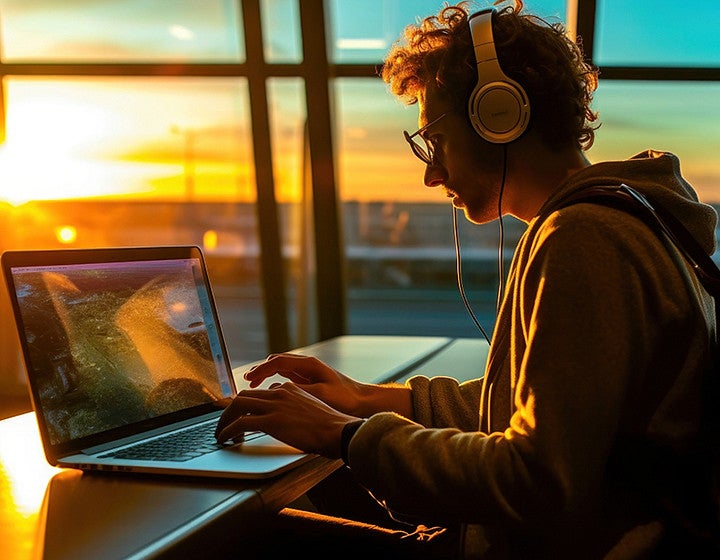 Freelance person working at the airport while commuting to home. Beautiful sunset at the airport departure terminal.