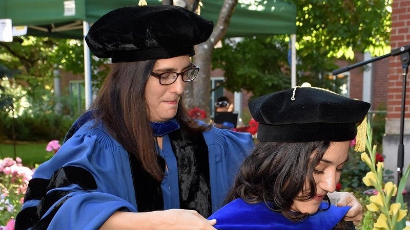 professors places graduate scarf on student at graduation