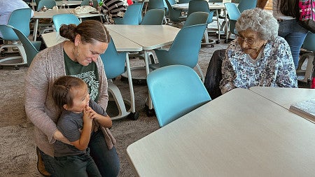 a child and woman talk with an Indigenous Elder