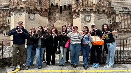 a group of students studying abroad, gathered for a photo doing the "O" pose