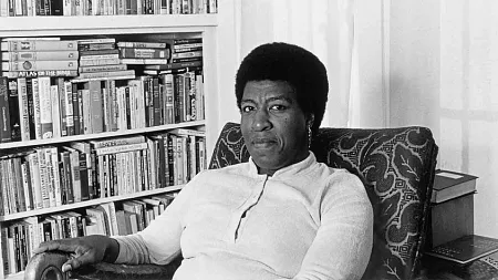 octavia butler sitting by a bookshelf