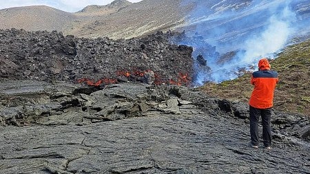 a man stands next to a lava flow