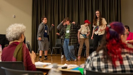 group of people dancing around on a stage as seen from the back of the room