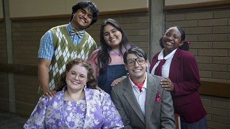 group of five people dressed in costumes like elementary school students and principals smiling at the camera 