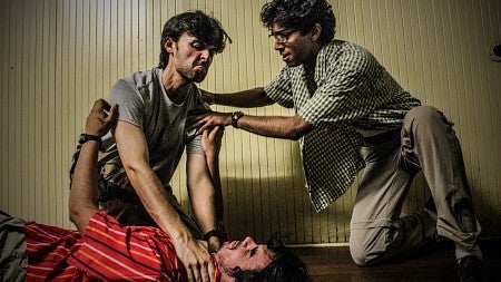 three men in conflict with one on the ground and another trying to stop the conflict
