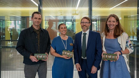 four people posing for a photo holding placards showing their award