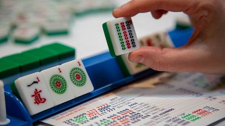 a person holding a mahjong tile with a more tiles standing up