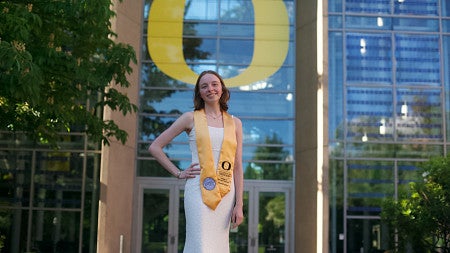 CAS female student standing in front of lillis business complex and big O