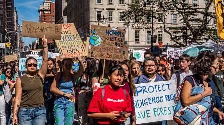 a group of protestors marching with signs about protecting Indigenous rights