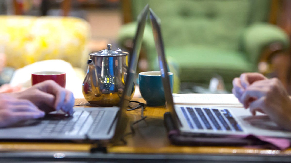 Close-up of two people working on laptops