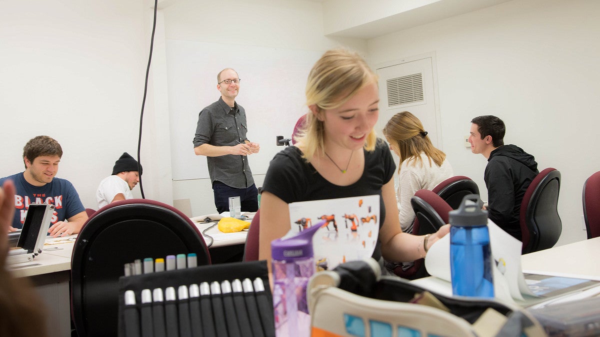 student and teaching smiling while working in large classroom of students