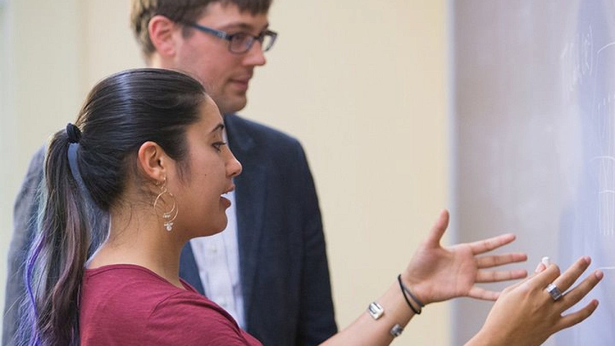 Student explaining something on blackboard