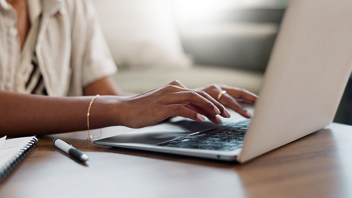 A person typing on a laptop sitting at a table