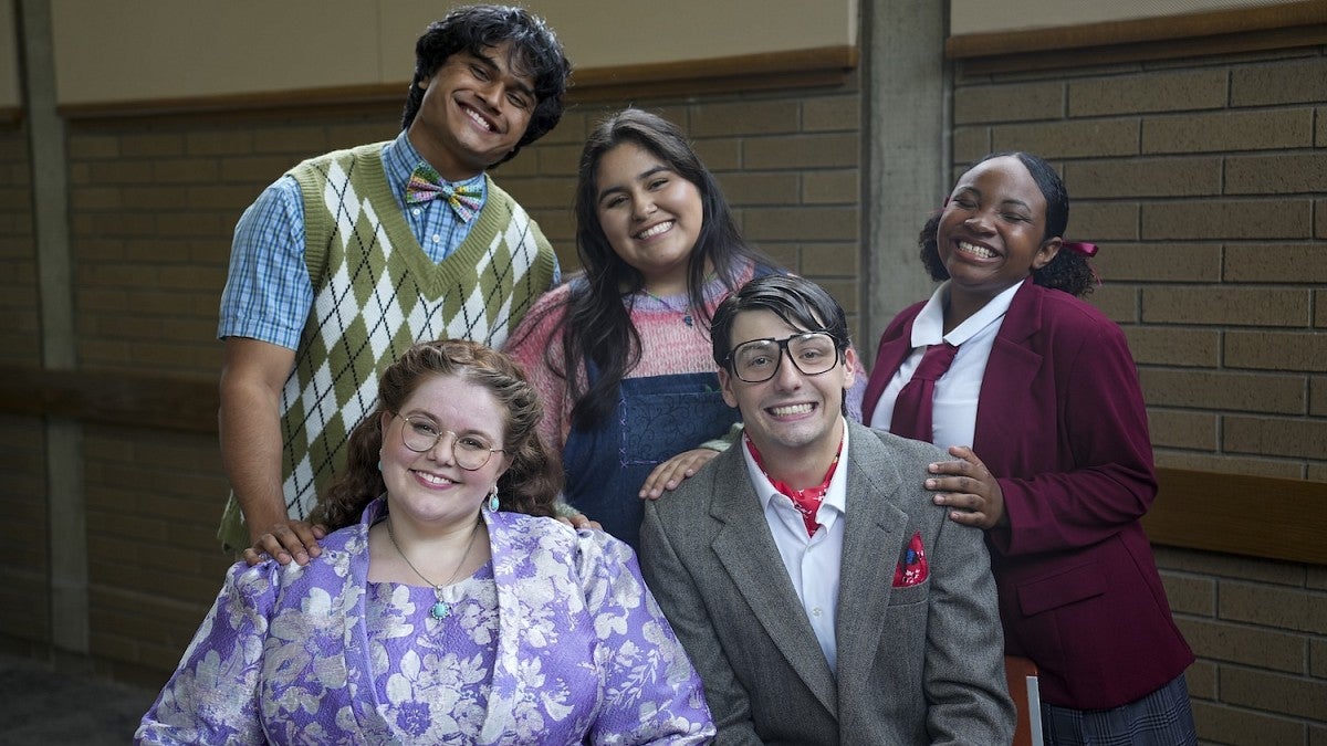 group of five people dressed in costumes like elementary school students and principals smiling at the camera