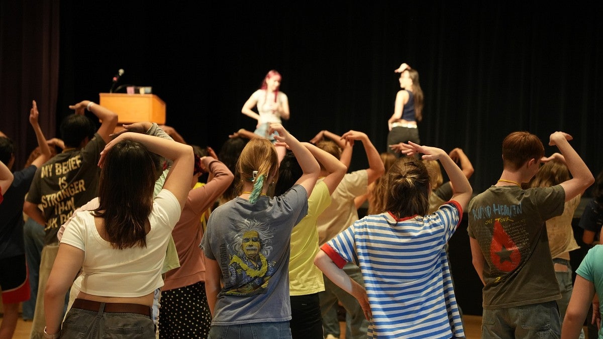 instructors on a stage teaching a crowd dance moves