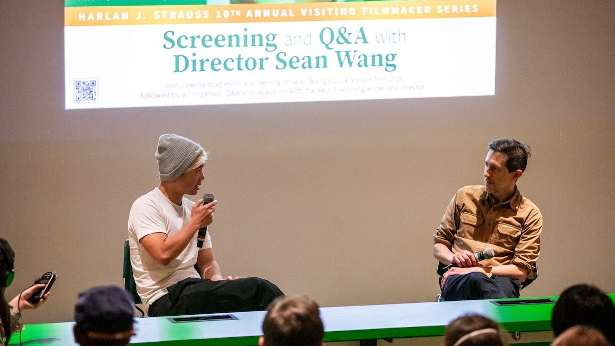 two men sitting on a stage holding microphones and having a conversation