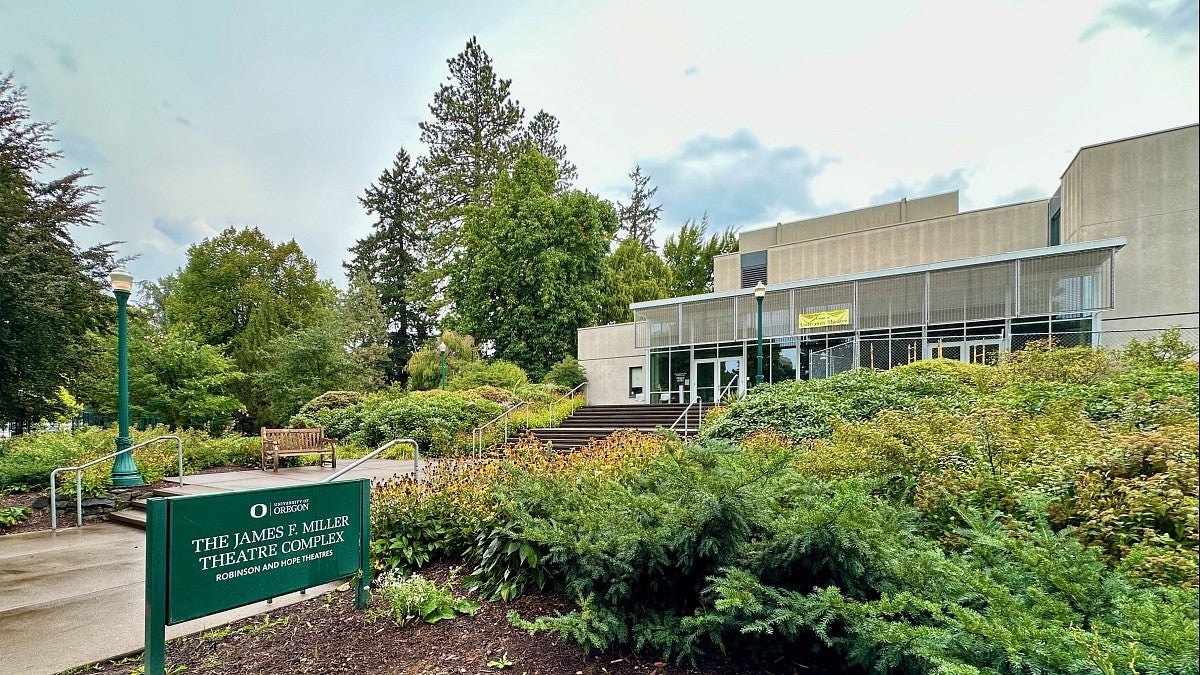 the front of miller theatre complex with trees and bushes and blue sky around it