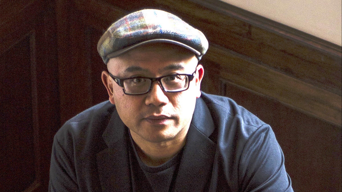 man wearing news cap and bold framed glasses looking at camera