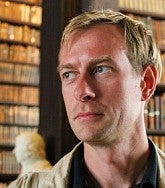 colin koopman, philosophy professor, poses in front of bookshelves