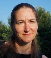 A woman with long brown hair standing outside