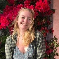 Blonde woman standing in front of red flowers 