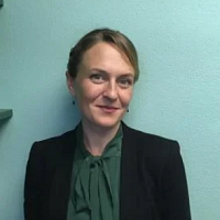 A woman with her hair pulled back standing in front of a blue wall