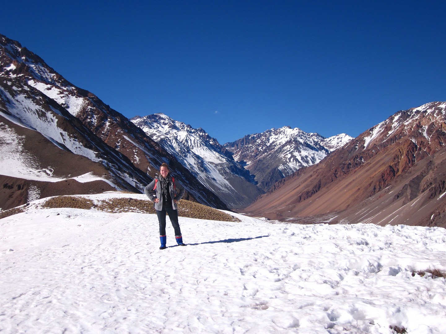 student on snow-covered slope with mountain range in background