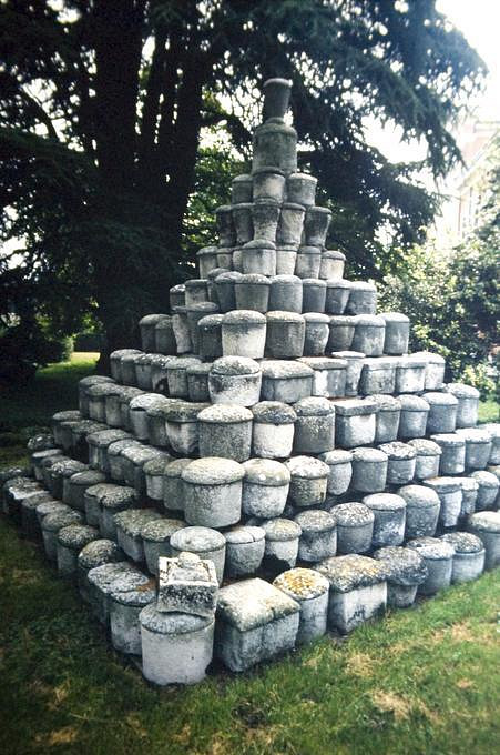 pile of stone jars with lids under tree
