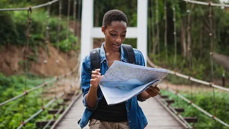 a hiker consults a map while crossing a bridge