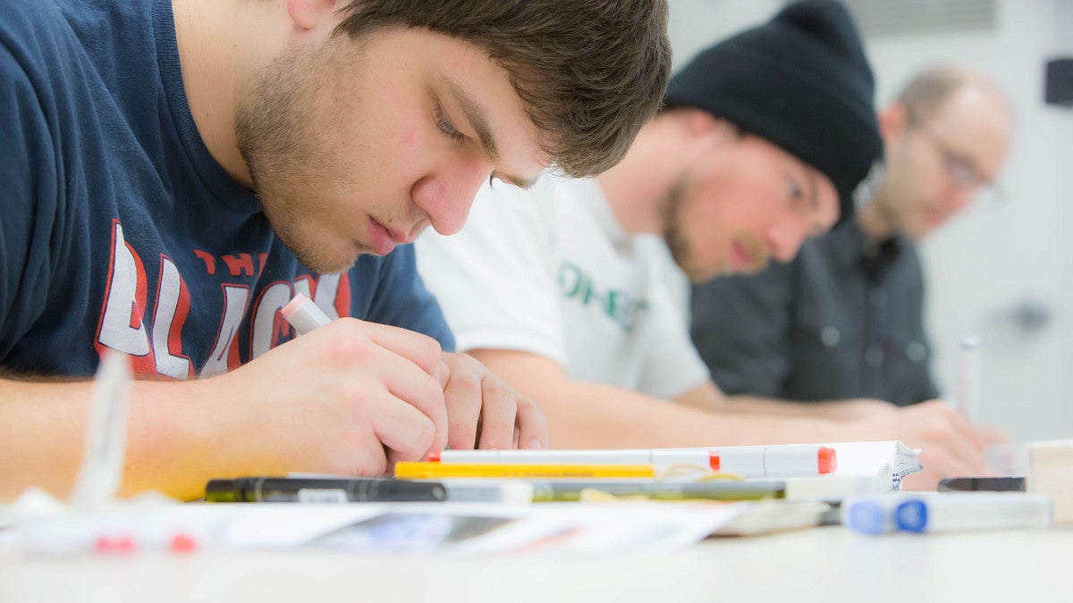 three students focused on coursework in class