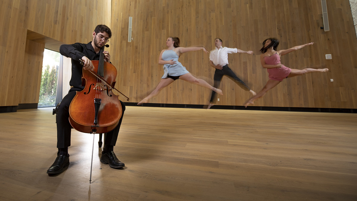 student playing the instrument while three other students dance behind him