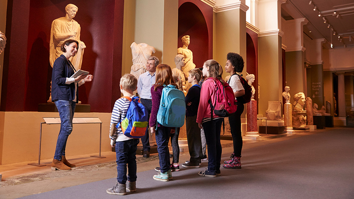 Pupils And Teacher On School Field Trip To Museum With Guide