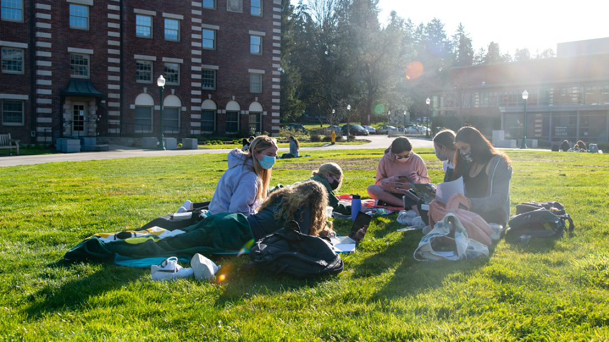 Students sitting on grass in front of building