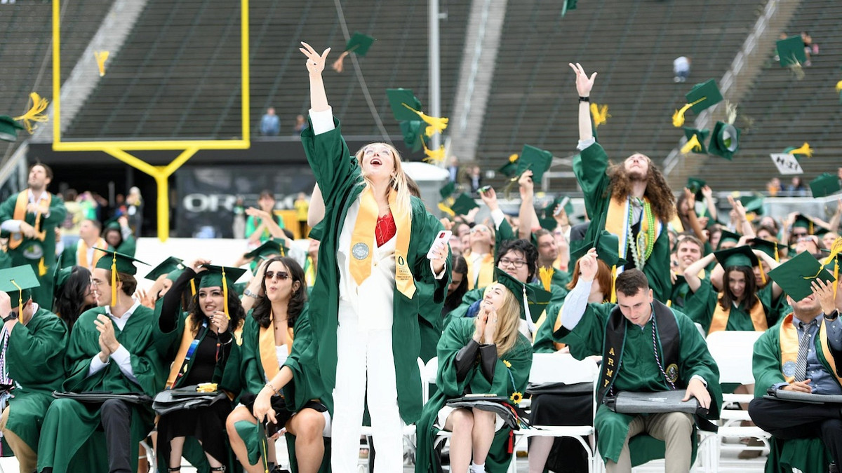 Graduates throwing hats in 2023 UO Commencement