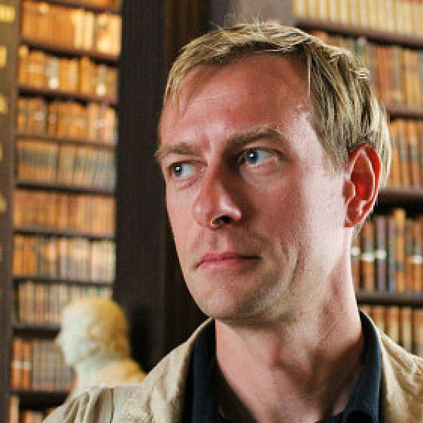 colin koopman, philosophy professor, poses in front of bookshelves
